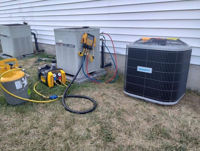 Old and new central air conditioner condensers side by side, with a refrigerant recovery machine, recovery tank, and gauges connected